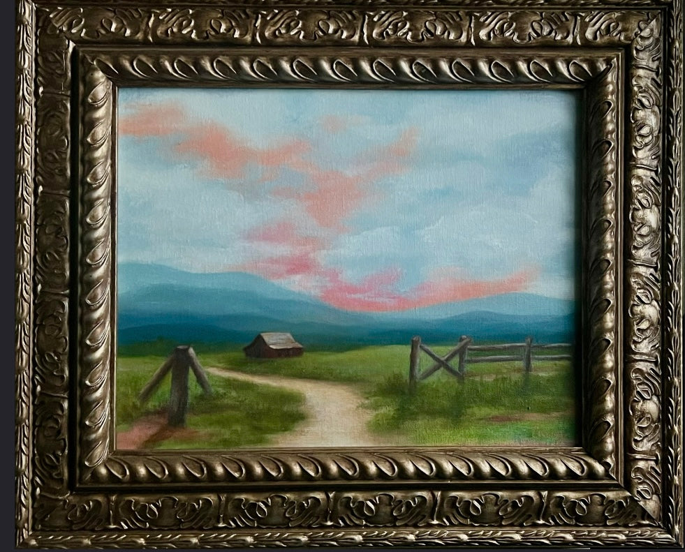 Framed oil painting titled Homestead Light, featuring a barn and field under a soft pink sunset sky with mountains in the distance.